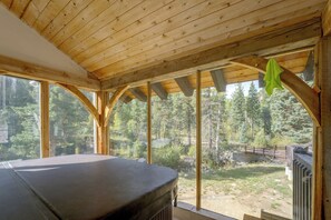 Une cabane en bois dotée d’une grande fenêtre et d’un bain à remous.