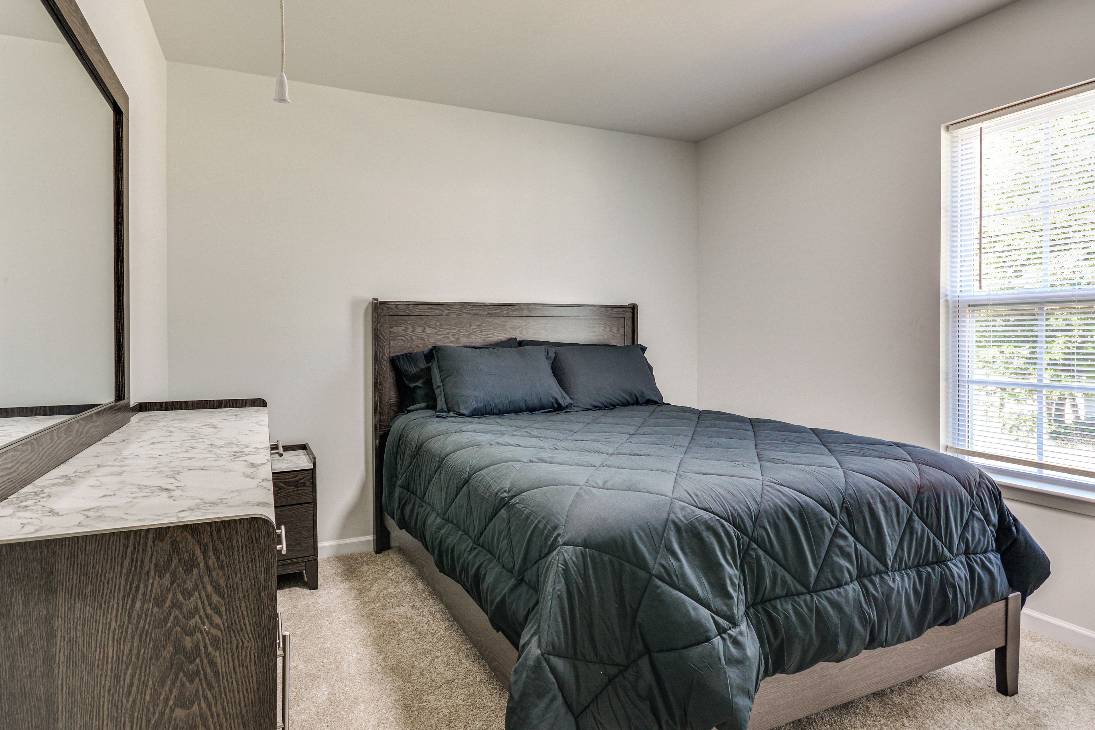 Une chambre à coucher avec un lit, une table de chevet, une commode et une fenêtre.
