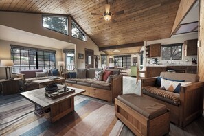 A spacious living area with a high ceiling, wooden furniture, and large windows providing natural light. - Big Bear Cabin w/ EV Charging, Fireplace & Deck! (Sugarloaf)