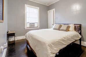 A bedroom with a bed, a window with blinds, a door, and a small table with a telephone. - Quaint Apt 6 Mi to Stadiums & Dtwn Detroit! (Detroit)
