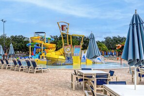 A water park with slides and a pool area with lounge chairs and umbrellas.
