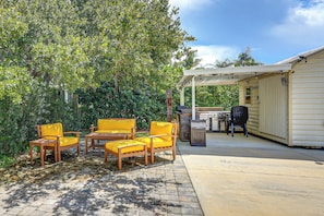 Een terras buiten met een overdekte zithoek en een barbecue.