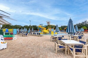 A poolside area with lounge chairs, umbrellas, and a water slide.