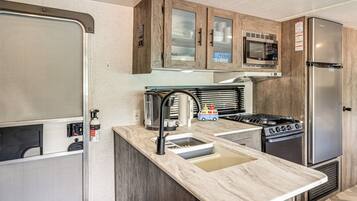 Una cocina compacta con estufa integrada, microondas y refrigerador.