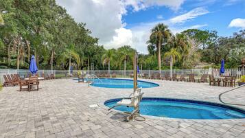A pool area with multiple swimming pools, lounge chairs, and umbrellas.