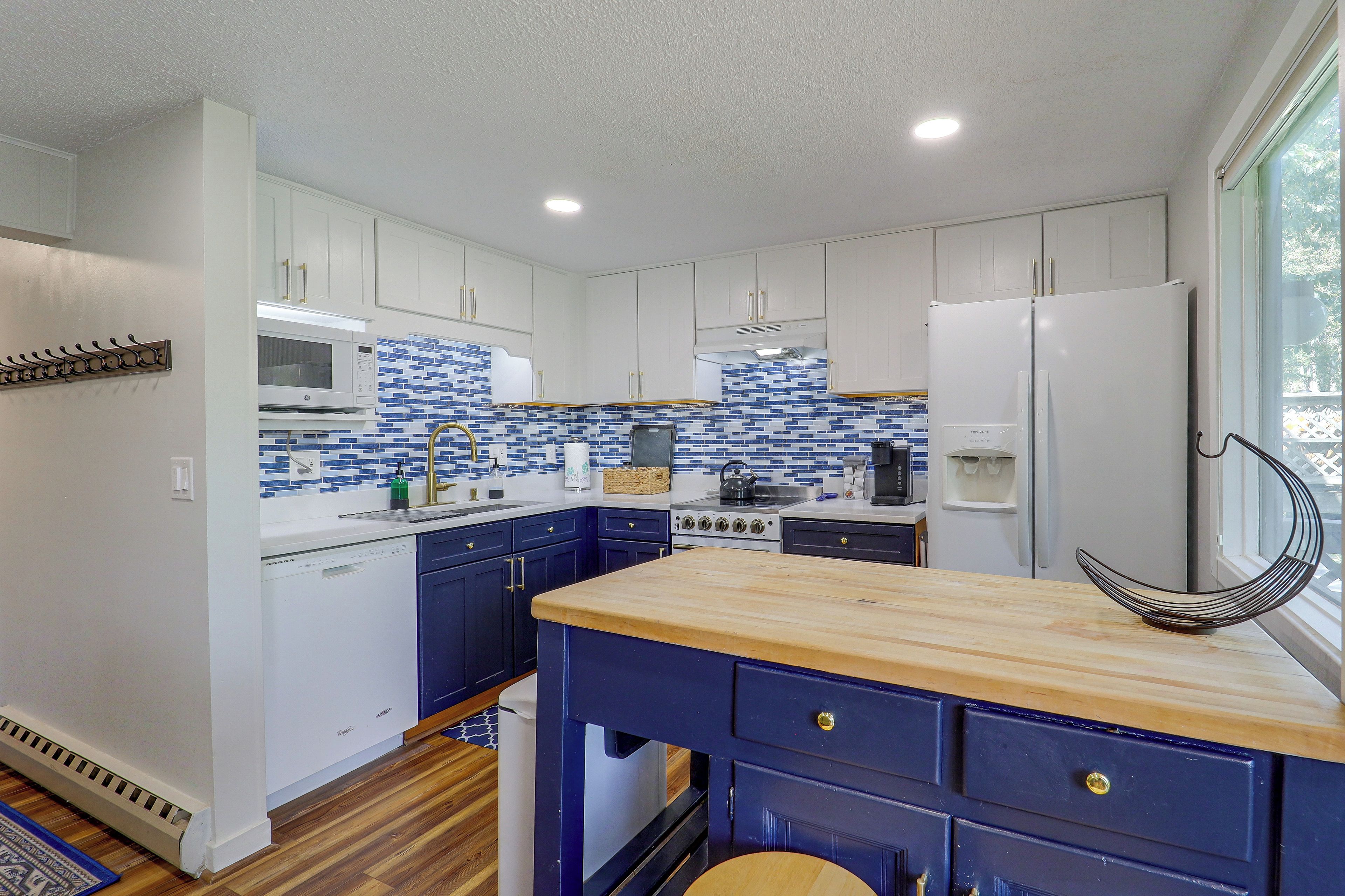 A modern kitchen with white cabinets, a blue tiled backsplash, and a wooden countertop.