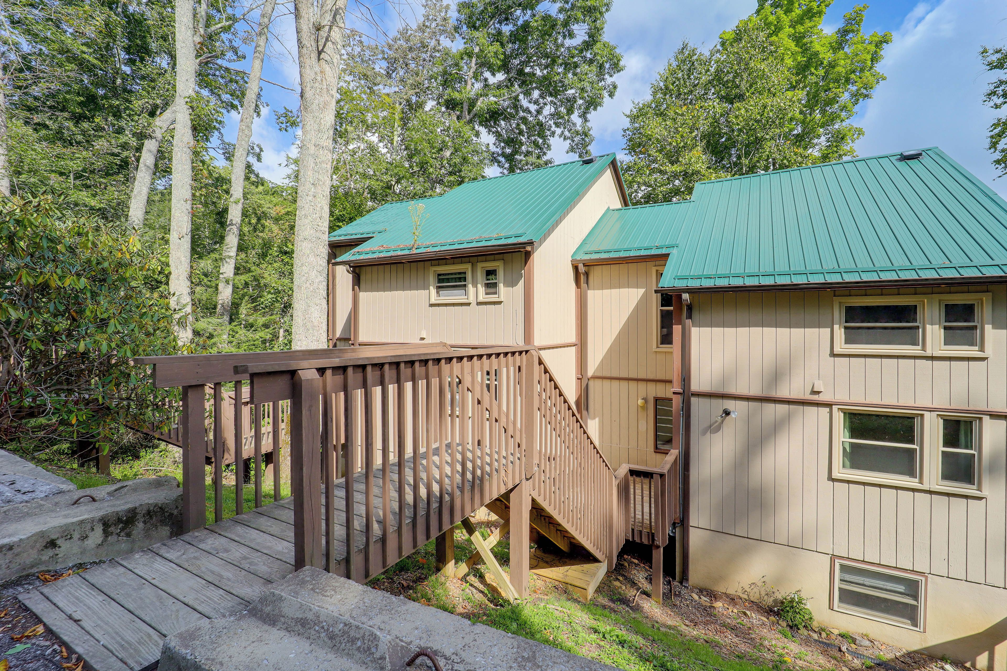 A two-story building with a green roof, a wooden deck, and a staircase leading to the upper level.