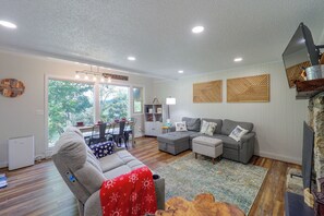 A modern living room with a sectional sofa, a dining area with a table and chairs, and a large window providing a view of the outdoors. - 3 Blocks to the Slopes! Sugar Mtn Ski Condo (Banner Elk)