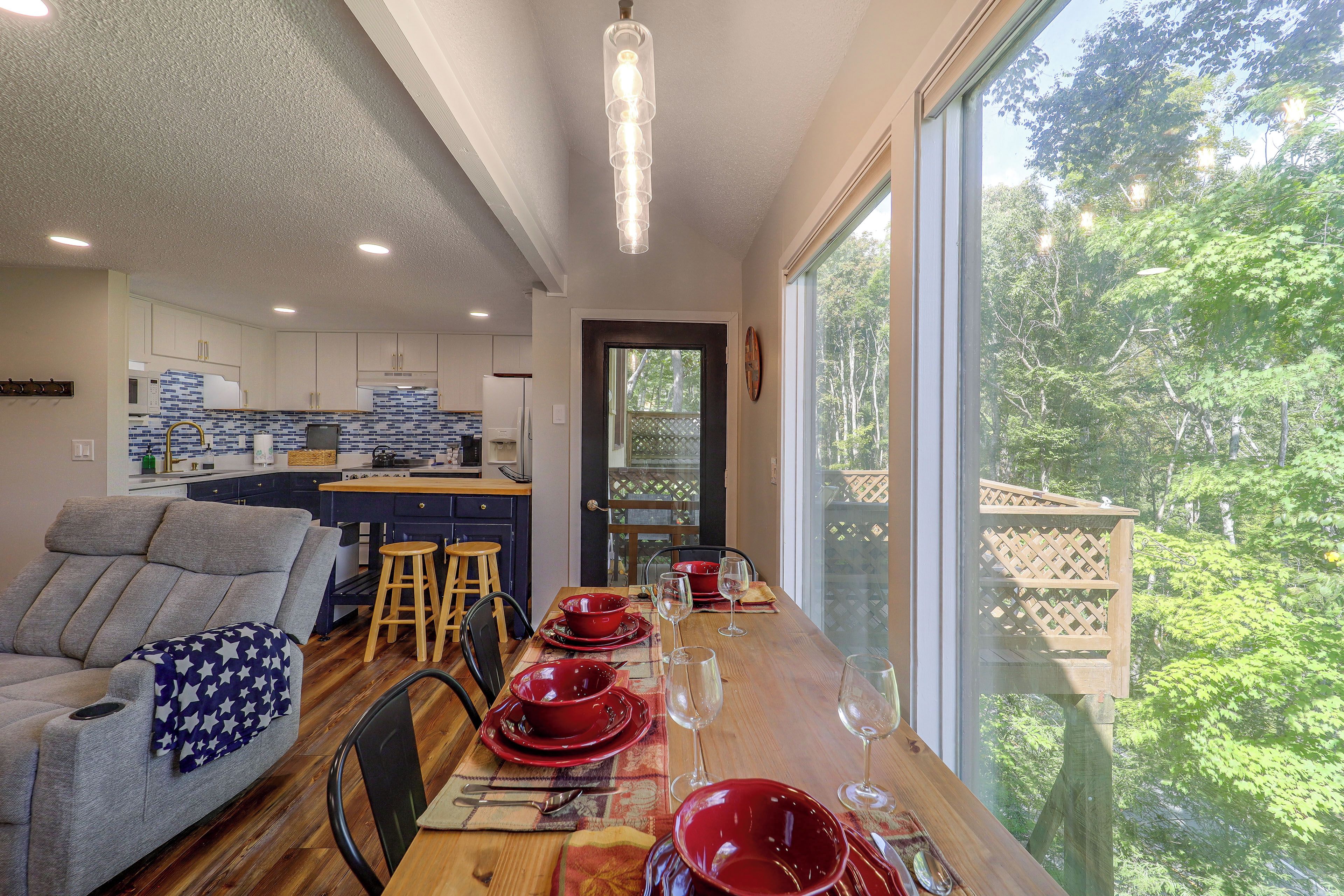 A modern kitchen with white cabinets, a blue backsplash, and a dining area with a wooden table set for two.