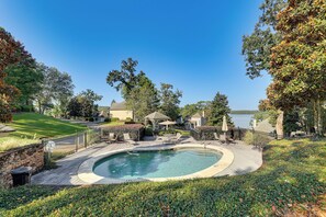 A residential property with a swimming pool, outdoor furniture, and a view of a lake.