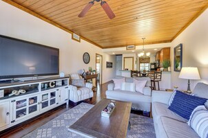 Amplia sala de estar con un televisor de pantalla plana grande, techo de madera, chimenea y comedor con candelabro.
