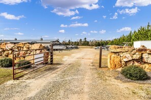 A gravel driveway leading to a gated area with a building and parked vehicles.