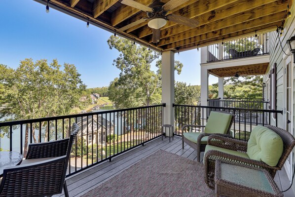 A covered outdoor area with wicker furniture and a view of a lake.