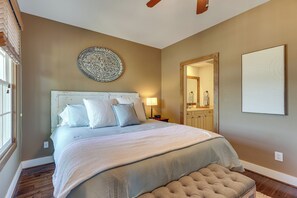 Un dormitorio con una cama, una mesita de noche, una lámpara, un espejo y un plato decorativo en la pared.