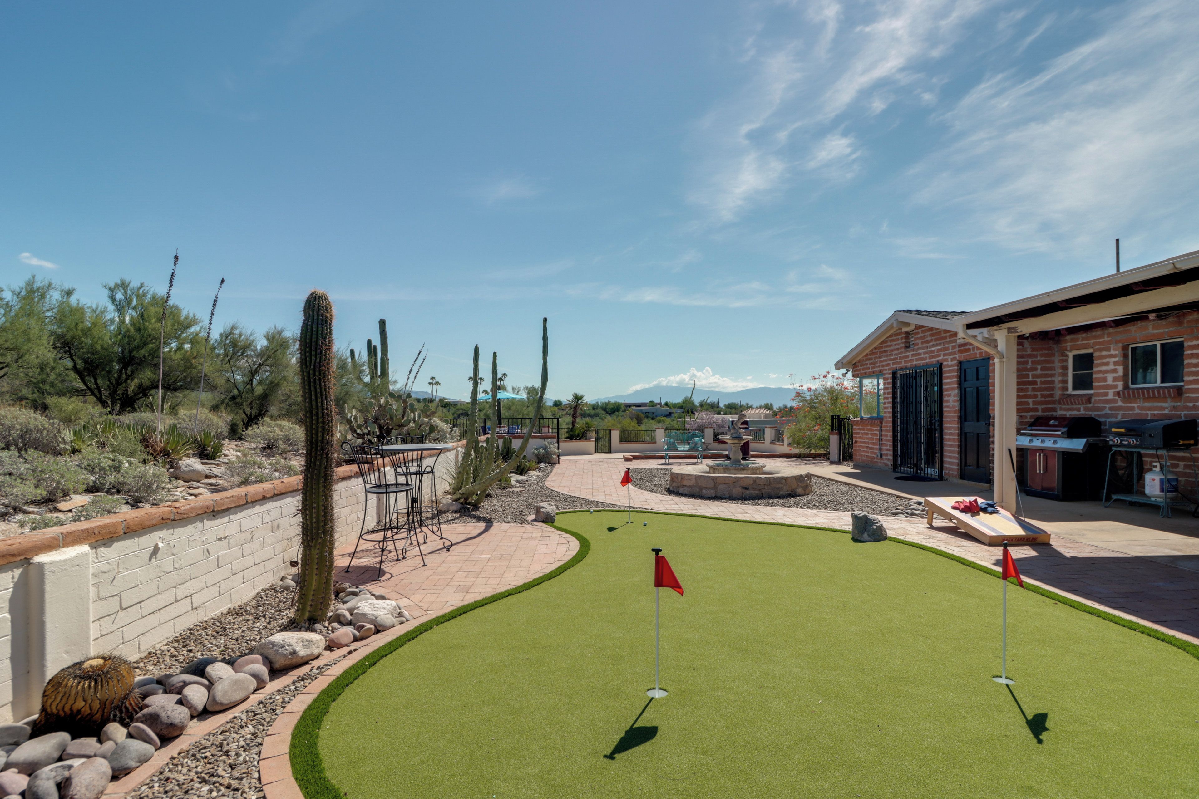 A golf course with a brick building and cacti in the background.