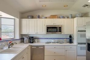 A modern kitchen with white cabinets, a microwave, a coffee maker, and a dishwasher. - Pool, Putting Green & Mtn Views: Tucson Home (Tucson)