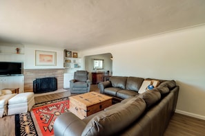 A living room with a leather sofa, a wooden coffee table, a fireplace, and a television. - Pool, Putting Green & Mtn Views: Tucson Home (Tucson)