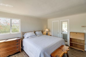 A bedroom with a bed, wooden dresser, bedside lamp, and a bench. - Pool, Putting Green & Mtn Views: Tucson Home (Tucson)