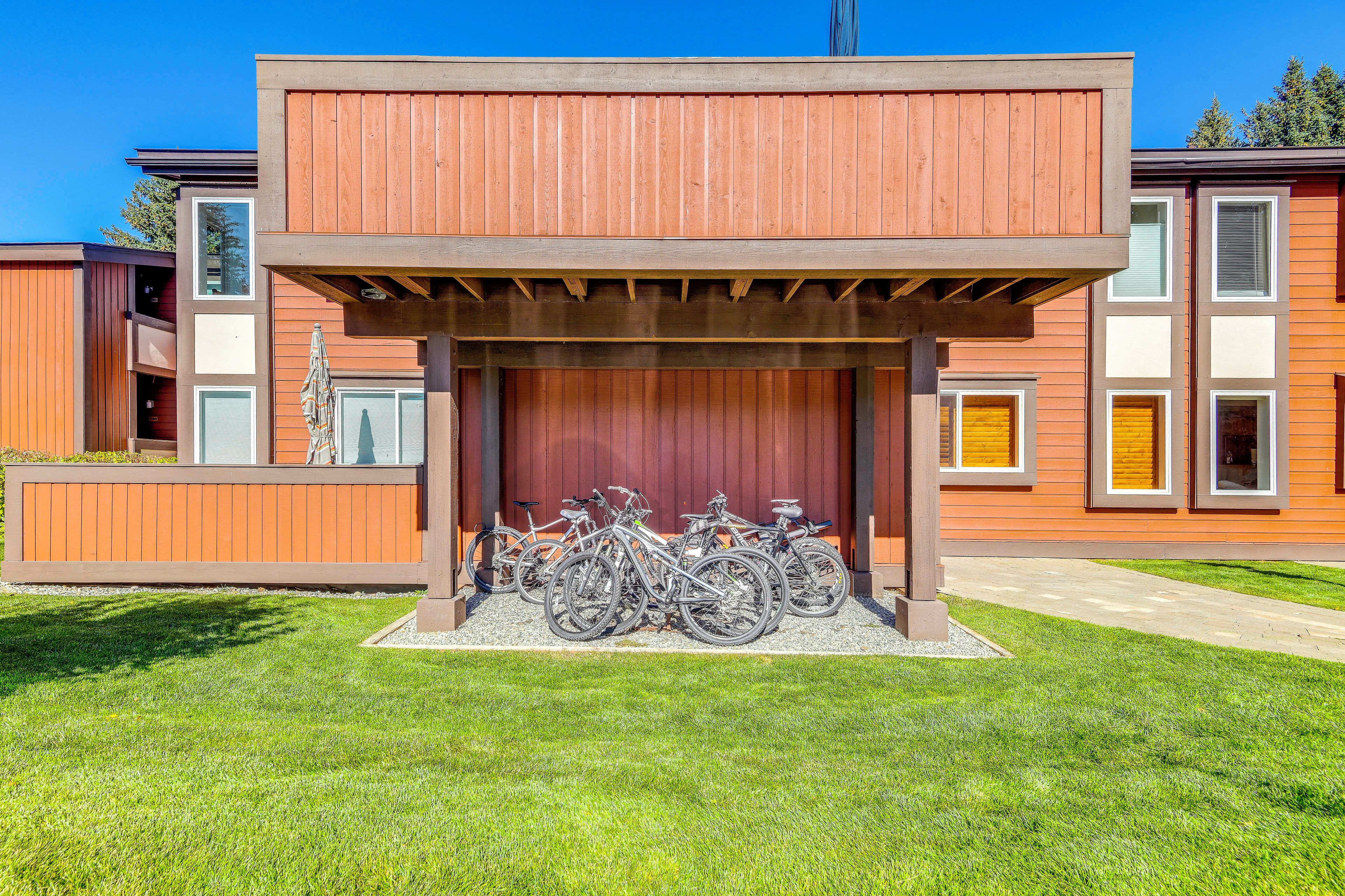 A building with a covered bike parking area and a grassy lawn.