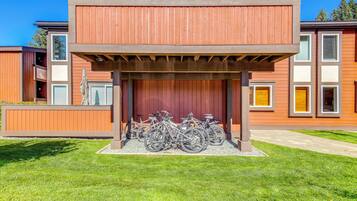 A building with a covered bike parking area and a grassy lawn.