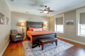 A bedroom with a large bed, a chair, a bench, a ceiling fan, and a window.