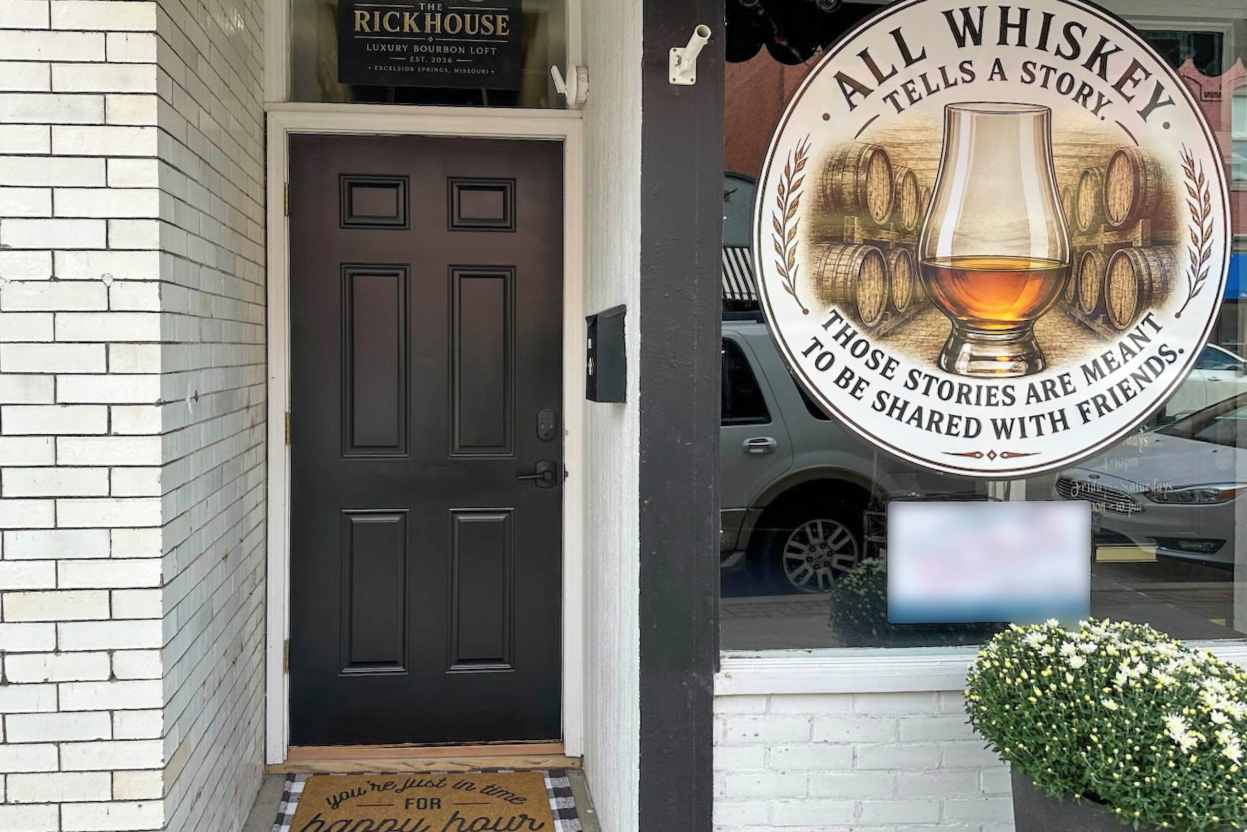 A brick building with a dark brown door and a sign above it that reads 'Rick House Luxury Bourbon Loft.'