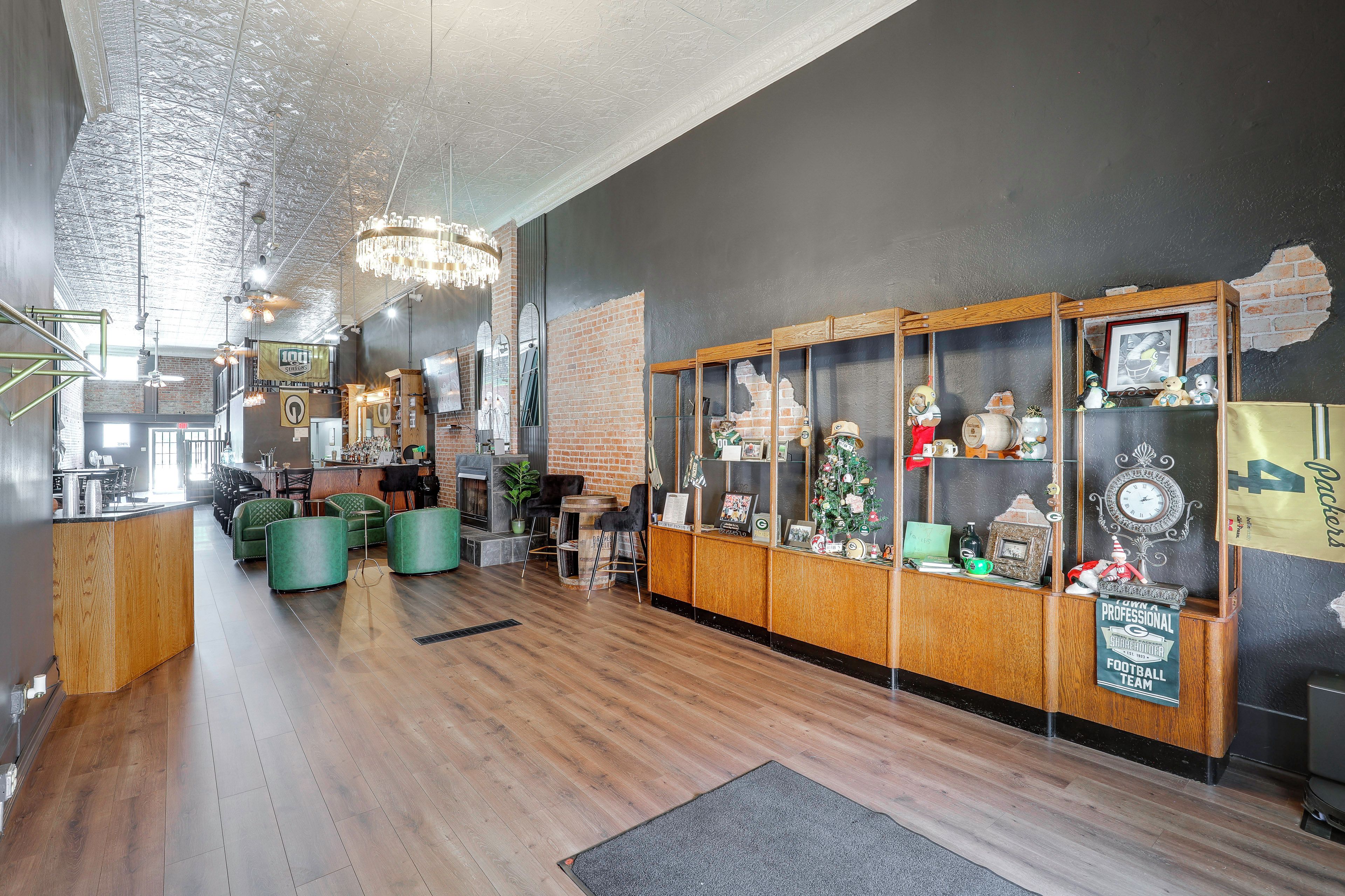 A bar area with wooden flooring, green seating, and a brick wall.
