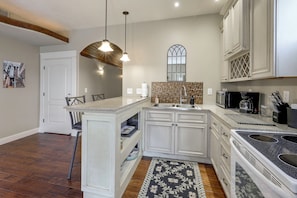 Una cocina moderna con armarios blancos, una isla central y un comedor con una silla.