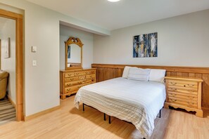Un dormitorio con una cama, cómoda de madera y un espejo.