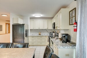 Una cocina moderna con armarios blancos, un refrigerador de acero inoxidable, una cafetera y un tostador.