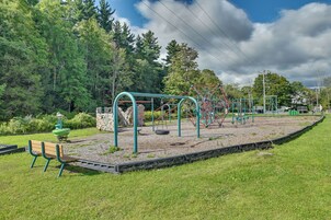 Un parque infantil con columpios, tobogán y banco.