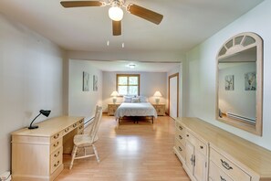 A bedroom with a bed, bedside tables, a desk, a chair, a ceiling fan, and a large mirror. - Game Room & Fire Pit! Creekside Catskills Retreat (Tannersville)