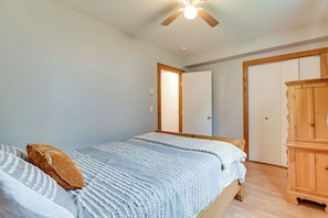 Ein Schlafzimmer mit einem Bett, einem Kleiderschrank, einem Deckenventilator und einer Tür zu einem anderen Raum.