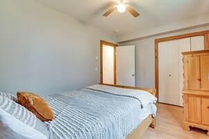 Un dormitorio con cama, armario, ventilador de techo y puerta que da a otra habitación.
