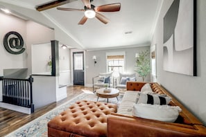 A spacious living room with a brown leather sofa, a round coffee table, and a ceiling fan. - Fire Pit & Fenced Yard! Peaceful Glen Carbon Home (Glen Carbon)
