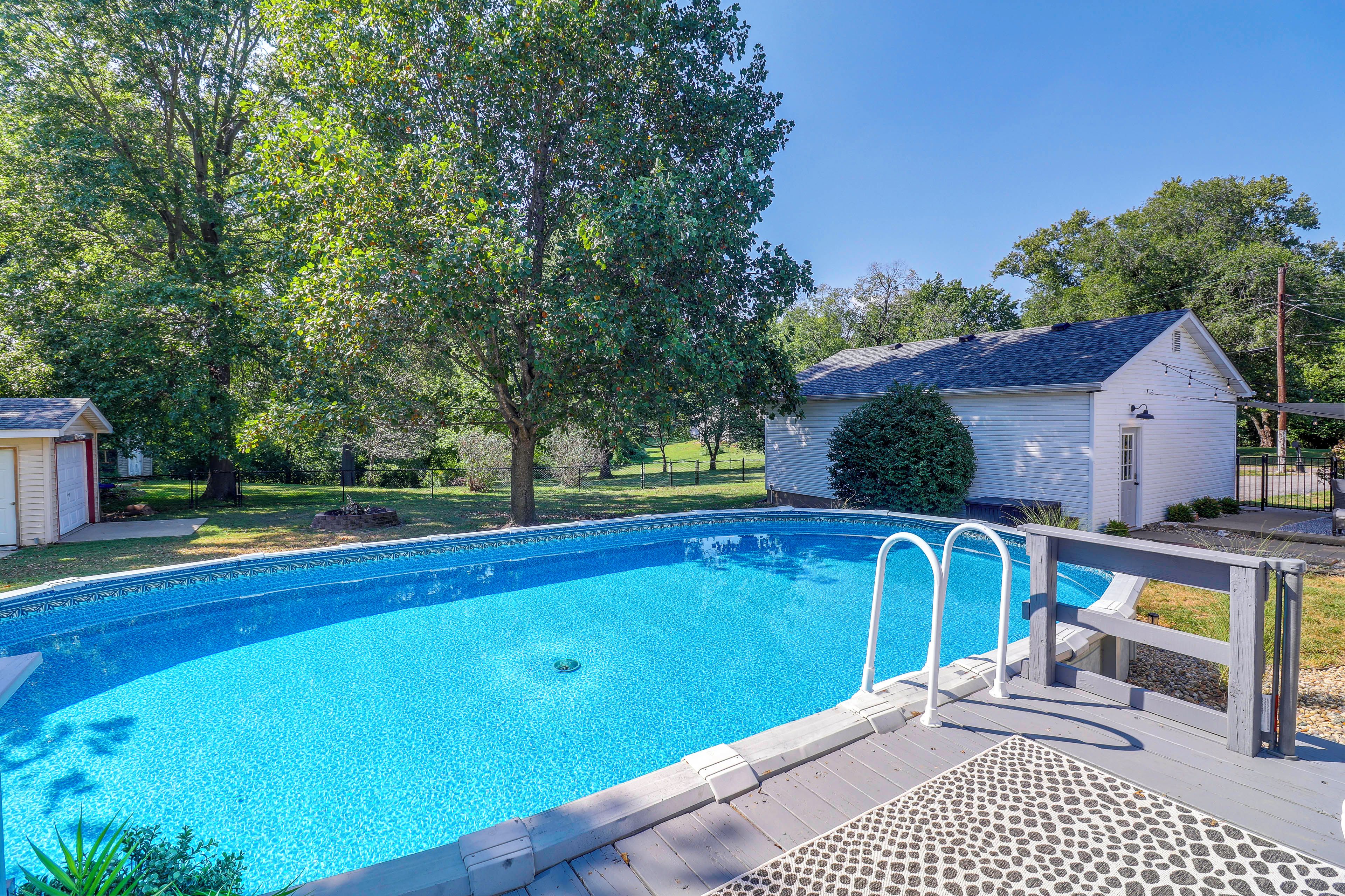 A clear blue swimming pool with a wooden deck and a metal ladder.
