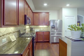 A kitchen with wooden cabinets, a stainless steel refrigerator, a microwave, and a gas stove. - Lewisville Lake Escape, 4 Mi to Boat Ramp (Little Elm)