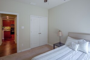 A bedroom with a bed, bedside table, lamp, and a door leading to a kitchen. - Lewisville Lake Escape, 4 Mi to Boat Ramp (Little Elm)