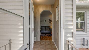 A hallway leading to a living room with a sofa and a fireplace.