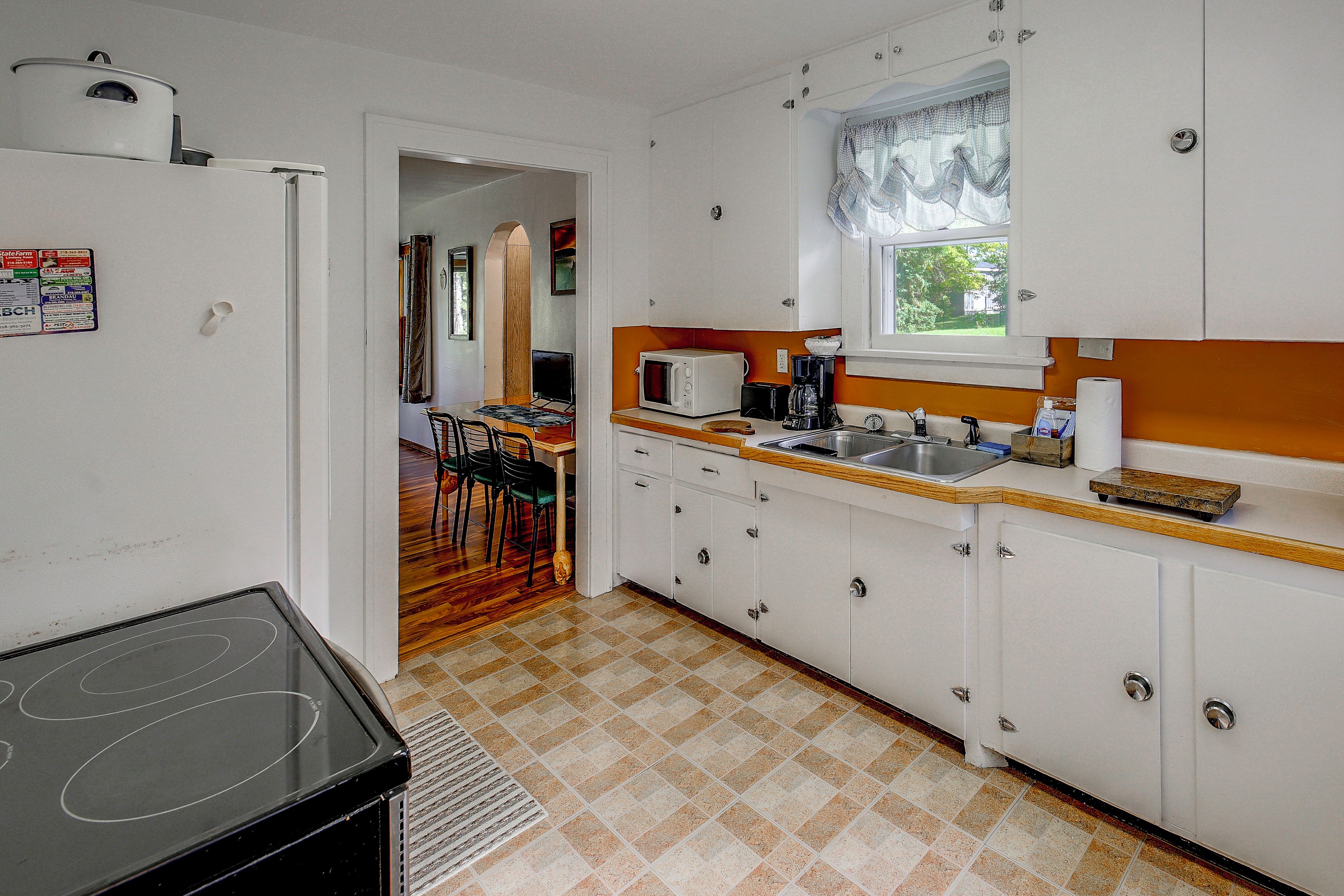 A compact kitchen with white cabinets, a microwave, a toaster, and a sink.