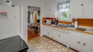 A compact kitchen with white cabinets, a microwave, a toaster, and a sink.