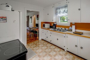 A compact kitchen with white cabinets, a microwave, a toaster, and a sink.