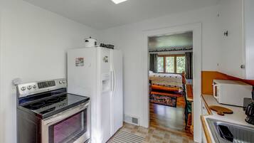 A compact kitchen with a stove, refrigerator, and microwave.