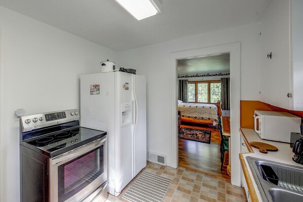 A compact kitchen with a stove, refrigerator, and microwave. - Paddle, Fish & Unwind: Shagawa Lake Home (Ely)