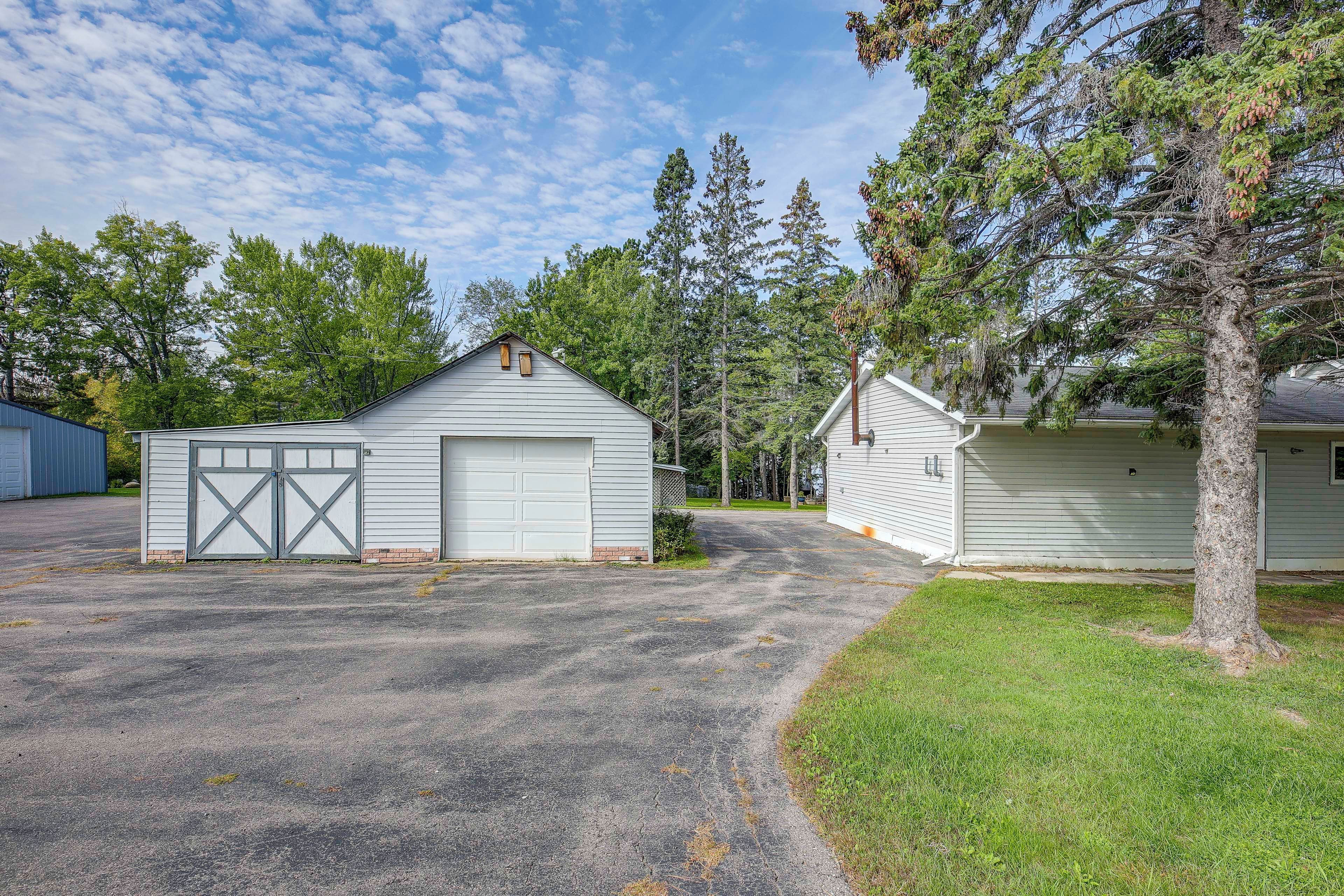 A property with a garage, a small shed, and a tree.
