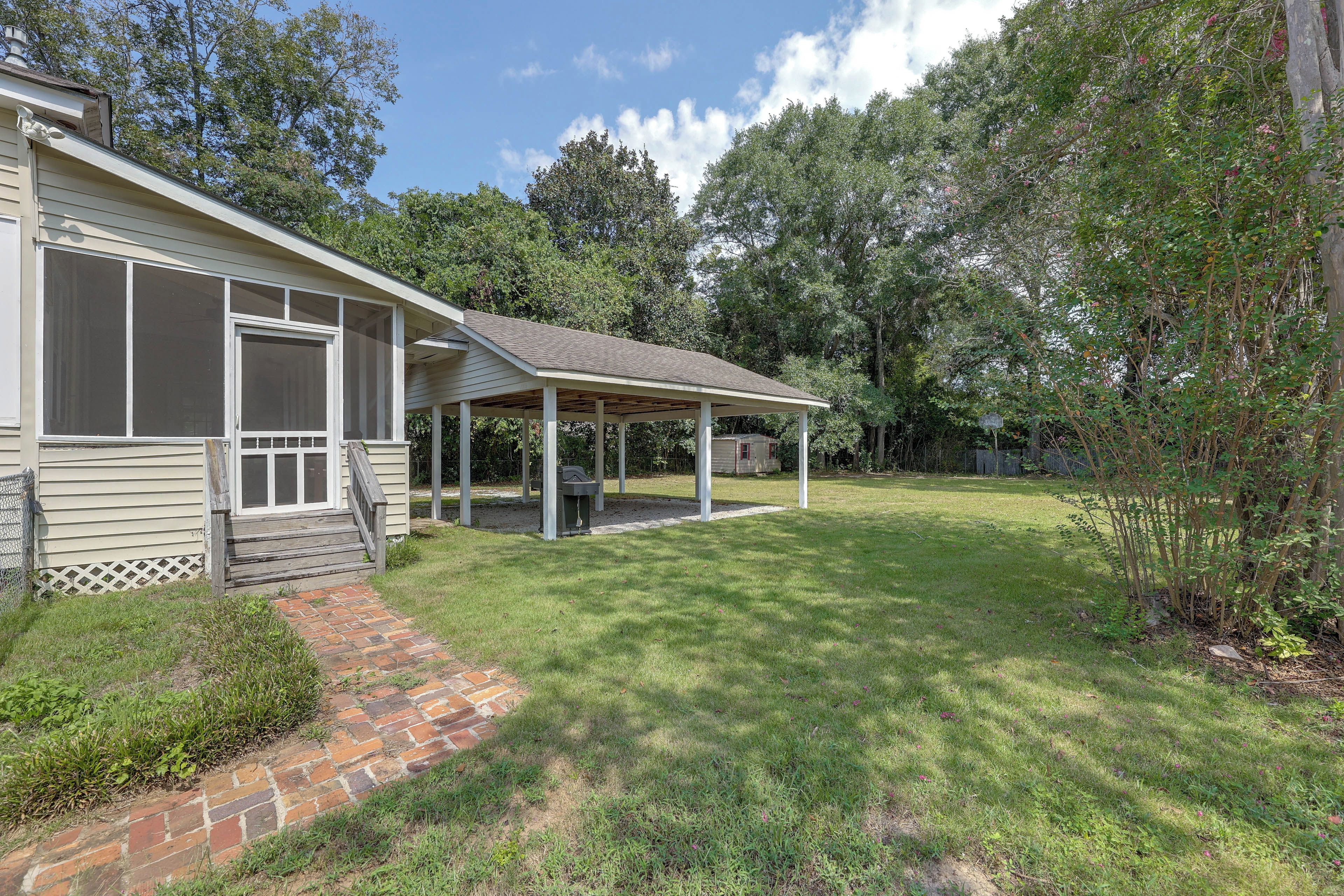 A house with a covered porch, a brick pathway leading to the entrance, and a grassy yard.