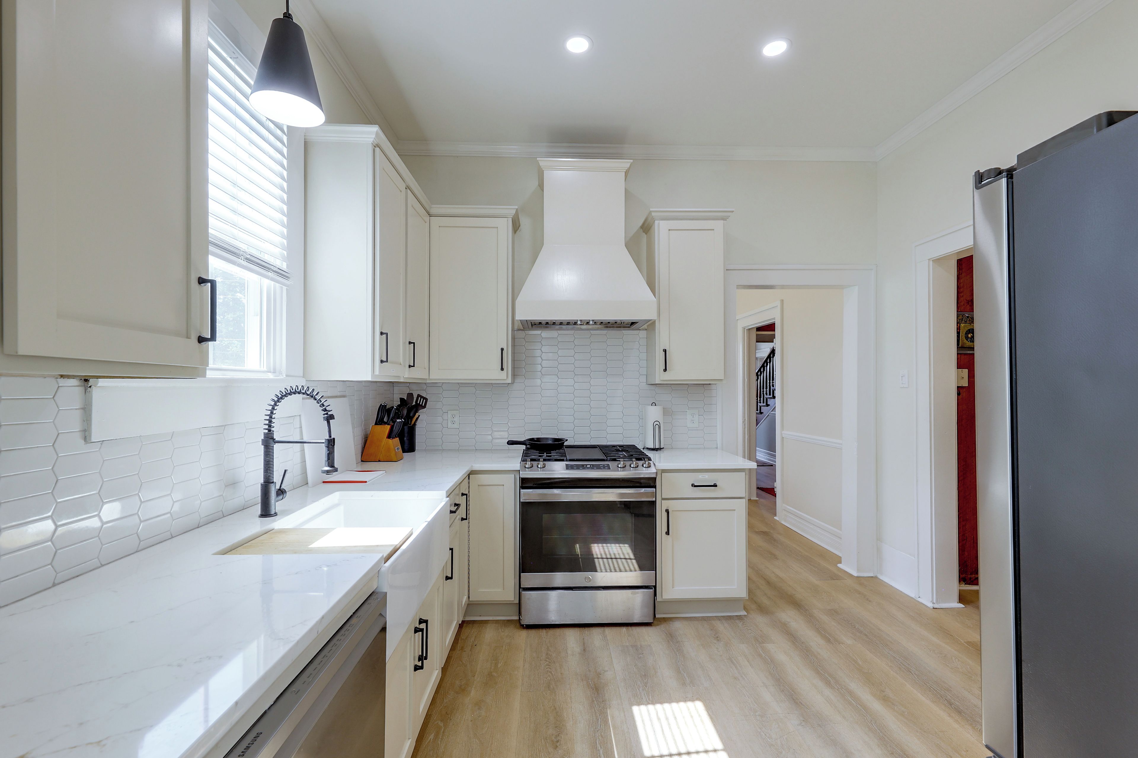 A modern kitchen with white cabinetry, a stainless steel stove, and a black refrigerator.