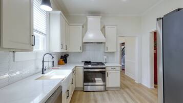 A modern kitchen with white cabinetry, a stainless steel stove, and a black refrigerator.