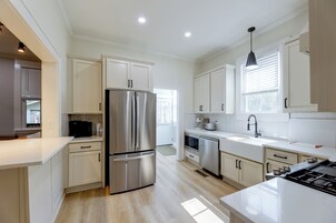 Una cocina moderna con electrodomésticos de acero inoxidable, armarios blancos y un amplio ventanal que proporciona luz natural.