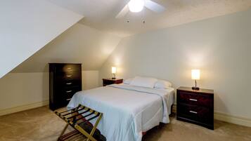 A bedroom with a bed, two bedside tables with lamps, a wardrobe, and a ceiling fan.